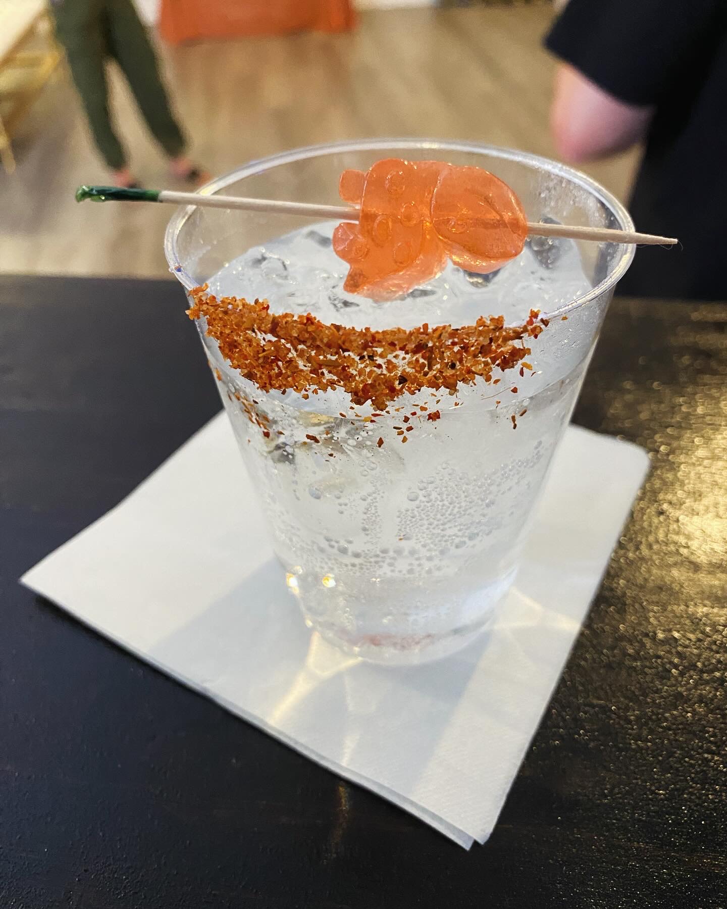 A Fiesty Mama cocktail rimmed with mixed spices and a toothpick skewering a watermelon vodka gummy bear