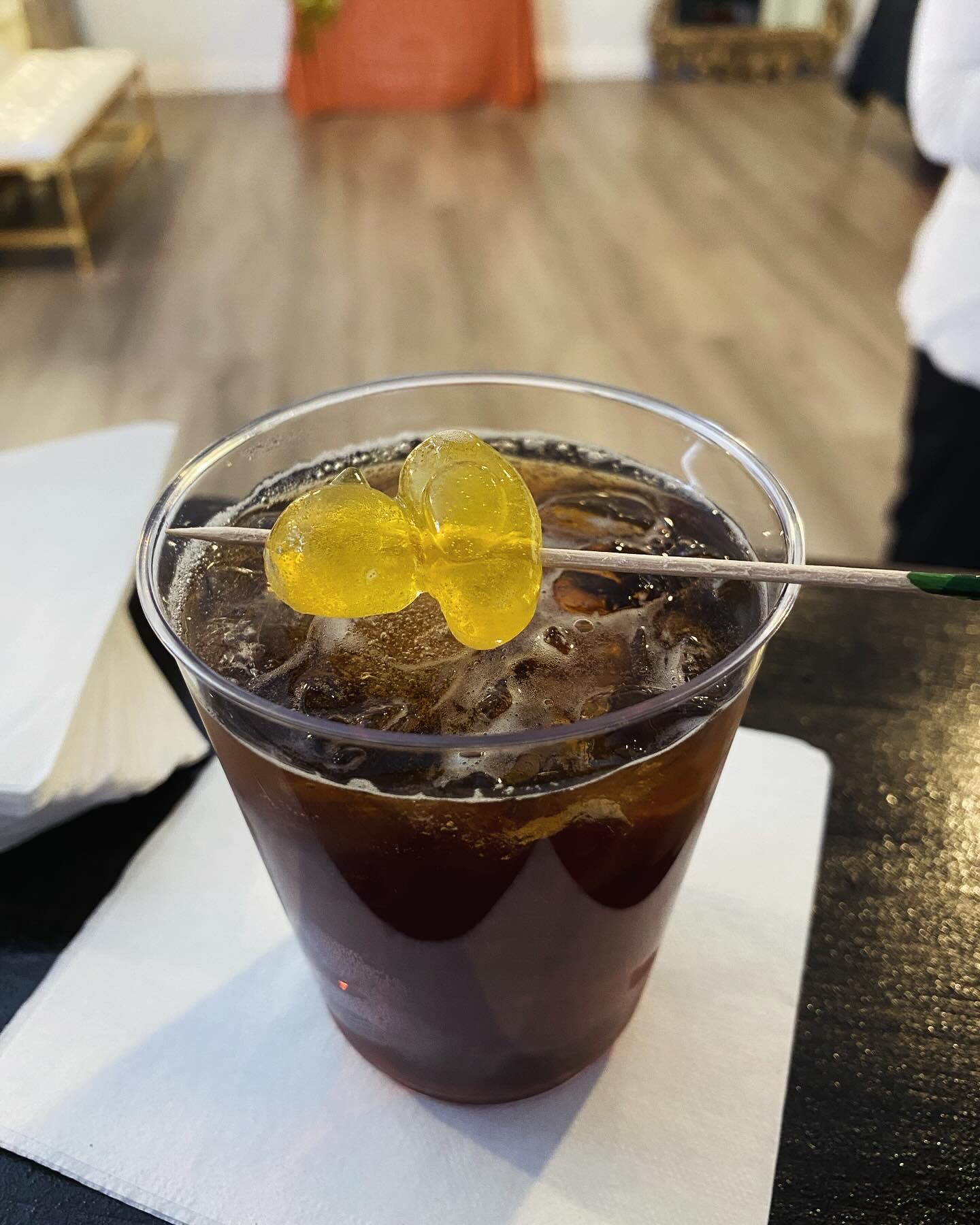 Bourbon and cola cocktail with pineapple gummy garnish.