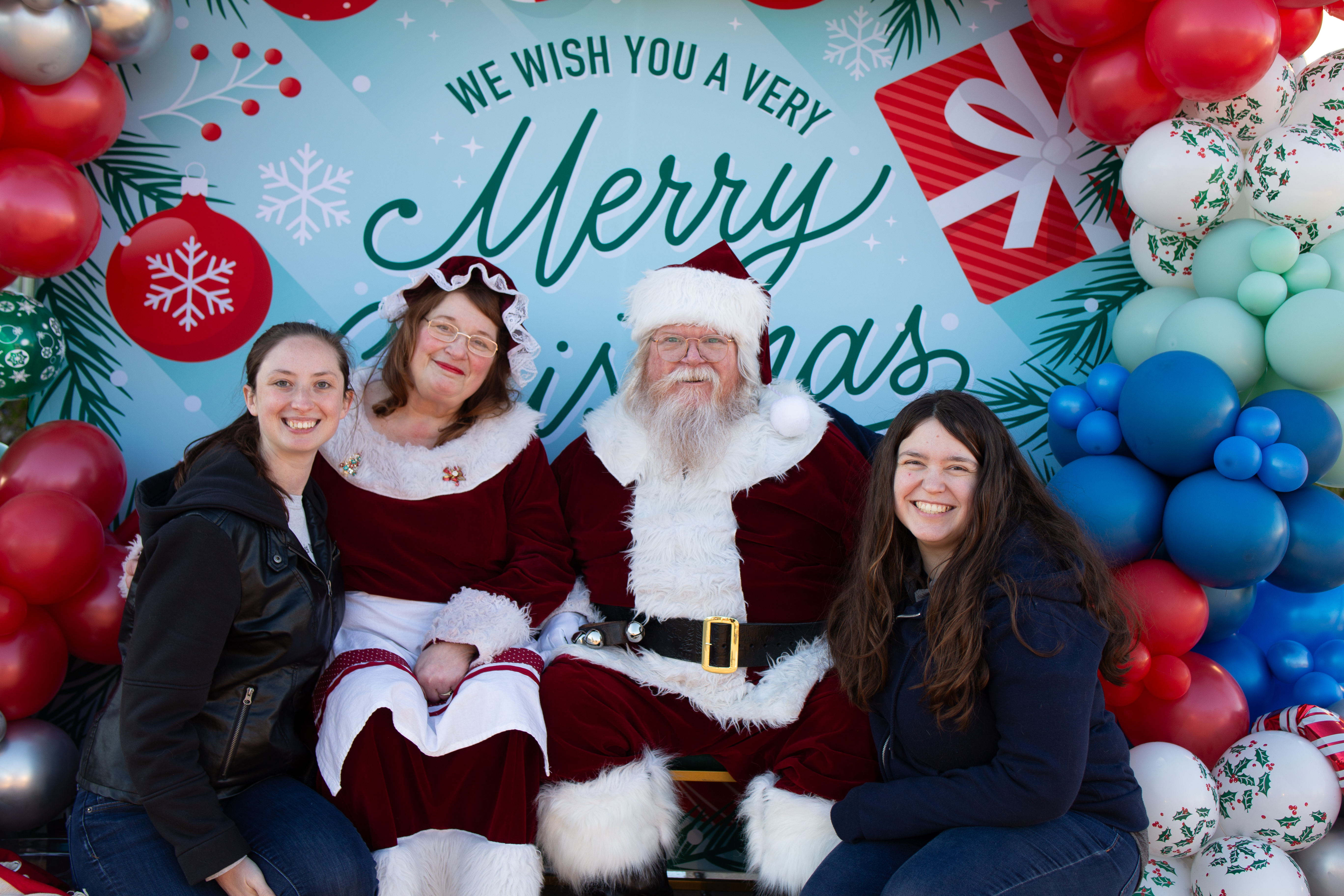 Two women sitting with Mr. and Mrs. Claus