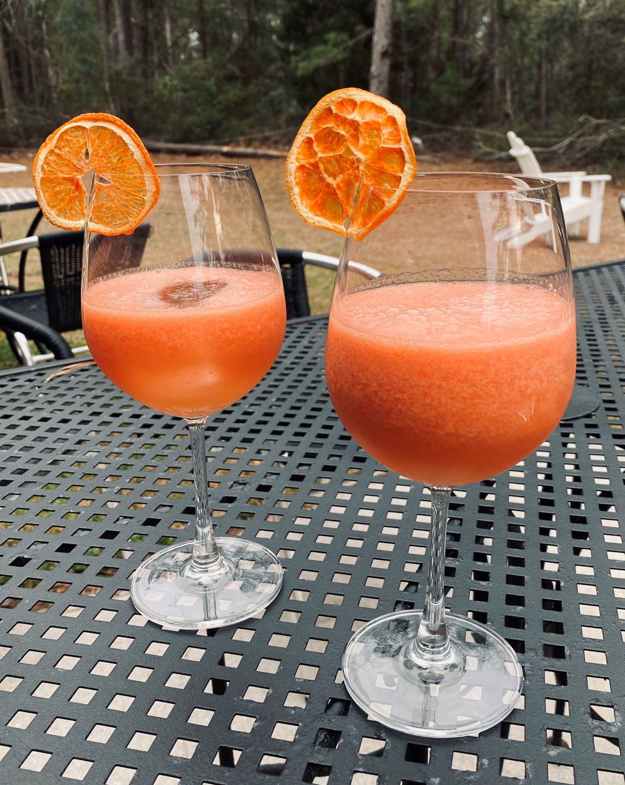 Two watermelon cocktails on a patio table rimmed with dried blood oranges